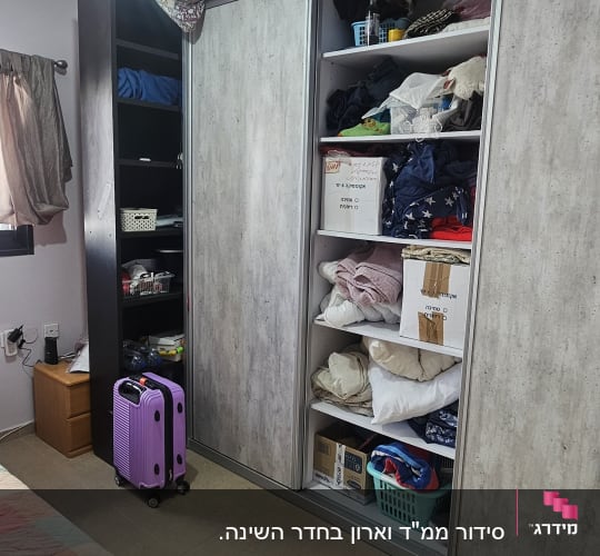 ארון בגדים פתוח עם מדפים מלאים בבגדים וארגזים